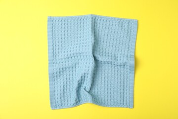 Light blue waffle towel on yellow background, top view