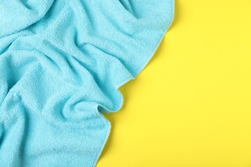 Light blue terry towel on yellow background, top view. Space for text