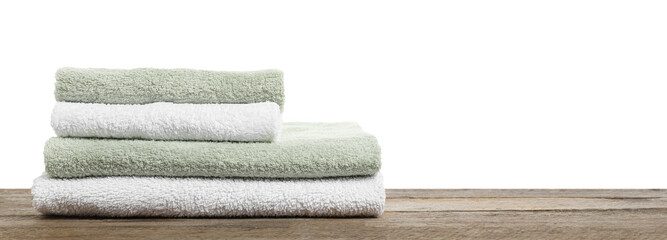 Stack of folded terry towels on wooden table against white background, closeup. Space for text