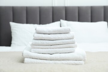 Stack of white terry towels on bed, closeup