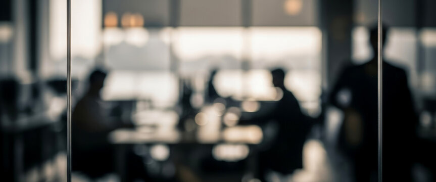 Blurred office scene shows people in a meeting around a table, collaborative team discussion in a bright open workspace that conveys professional interaction.