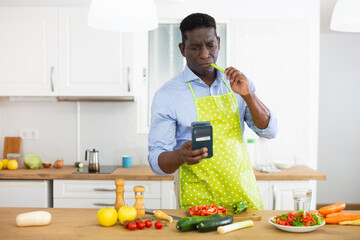 Man using smartphone while preparing food at home