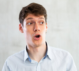 Portrait of young surprised guy in studio