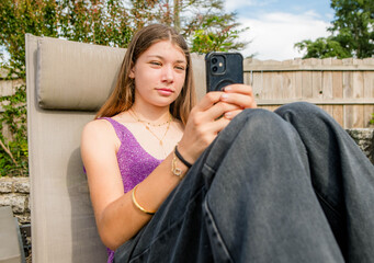 Beautiful young girl using her cell phone in the garden