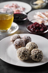 Delicious energy balls with sesame seeds and coconut flakes on a white plate.