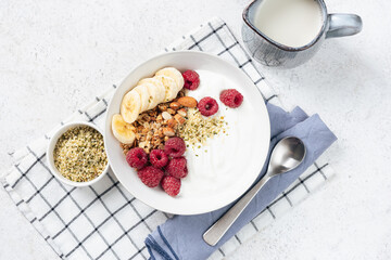 Granola bowl with yogurt, raspberries and banana slices. Table top view. Healthy food for diet, weight loss