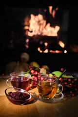 Cozy autumn scene with tea, jam, and a warm fireplace in the background.