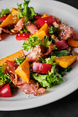 Delicious salad with bacon and fresh vegetables on a white plate.
