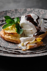 Delicious dessert with ice cream and chocolate sauce on a decorative plate.