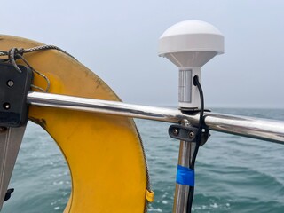 A GPS receiver aerial located to the top of the pushpit of a sailing yacht, used to provide latitude and longitude information to navigation instruments like chartplotters, logs and radar
