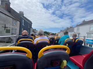 Passengers on the top open floor of an open top bus on a summer trip in Portland Dorset UK