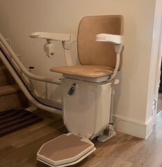 A stair lift or chair lift at the bottom of the stairs in a home. Used to help people with dissabilities, the elderly and those prone to falling to go upstairs and downstairs in their homes.