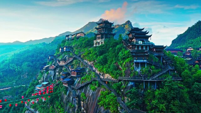Aerial shot of a stunning traditional Chinese village built on a steep cliffside with red lanterns and temples in the mountains.
