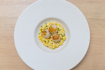 A plate of creamed corn with scallops on top.