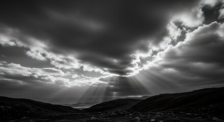 Dramatic sunbeams breaking through dark storm clouds over rugged landscape