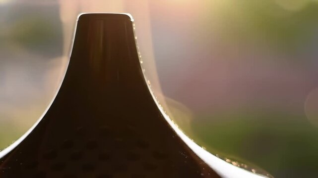 Serene close-up of a modern essential oil diffuser backlit by a warm, glowing light creating a relaxing spa-like atmosphere