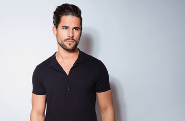 Handsome young man with dark hair and beard posing in casual clothes