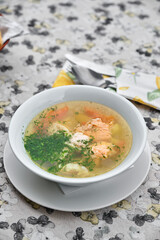 A delicious bowl of salmon soup served on a table with a floral tablecloth.
