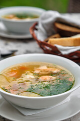 Delicious soup served in a white bowl with bread on the side