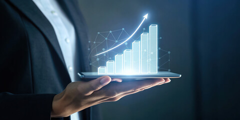 Businessman holding digital tablet with glowing rising bar chart and arrow showing growth