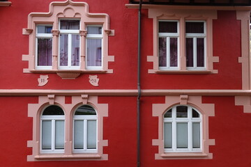 Architettura storica europea: finestre ornate su facciata rossa vivace con dettagli decorativi in stucco