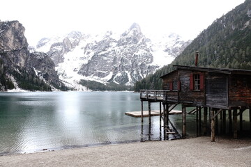 Lago di Braies in inverno con neve sulle Dolomiti e palafitta in legno, atmosfera serena e paesaggio alpino mozzafiato.