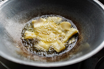 Close-up shot captures pieces being fried in a metal wok, sizzling in hot oil, ready to be enjoyed. Cooking food with bubbles creating a tasty delight, isolated in white background.