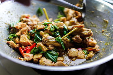 Delicious Thai basil chicken in a wok, seasoned with hot chili peppers and fresh basil. Mouthwatering homemade meal, isolated on white background. Ready for serving and enjoying the exotic flavors.