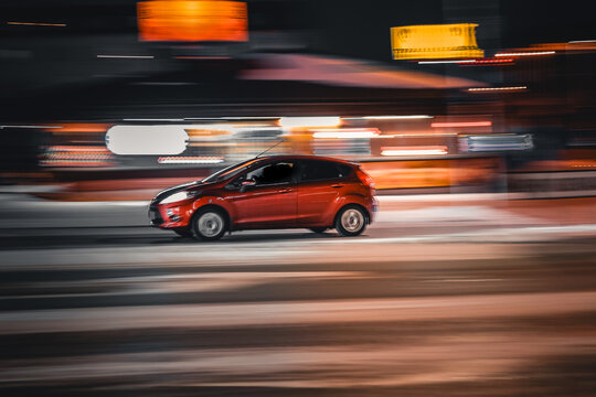 Red car driving fast in motion at night city street