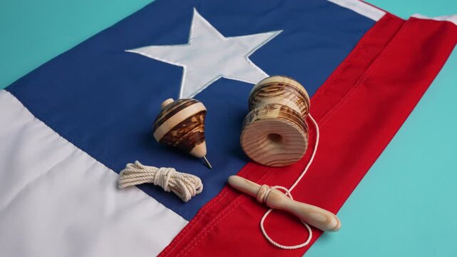 Traditional chilean wooden toys, a spinning top and a yo-yo, lying on the national flag