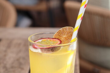 Passion fruit spritzer with half passion fruit and yellow striped straw – refreshing tropical drink