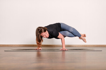 Naklejka premium Focused yoga pose on wooden floor