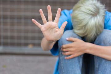 Lonely teenager showing a stop sign sitting on the floor