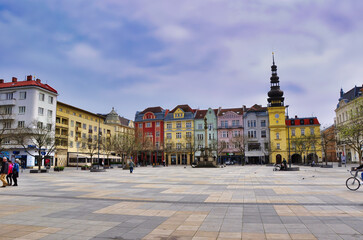 Ostrawa - panorama rynku starego miasta. Tętniący życiem rynek miejski z pastelowymi budynkami i wysoką wieżą zegarową.  © Pol Badger