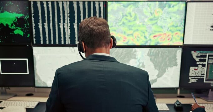 Man, computer and screen with date in control room, monitor weather and climate change. Back, meteorologist and headset with alert for hurricane update, study storm pattern and disaster surveillance