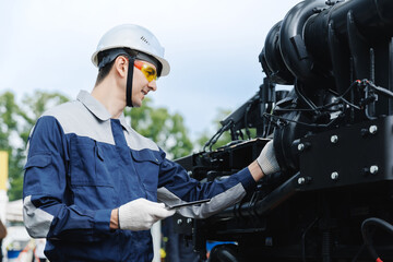 Obraz premium Mechanic with tablet computer diagnostics of diesel engine from industrial truck in garage. Fix service repair industry lorry concept