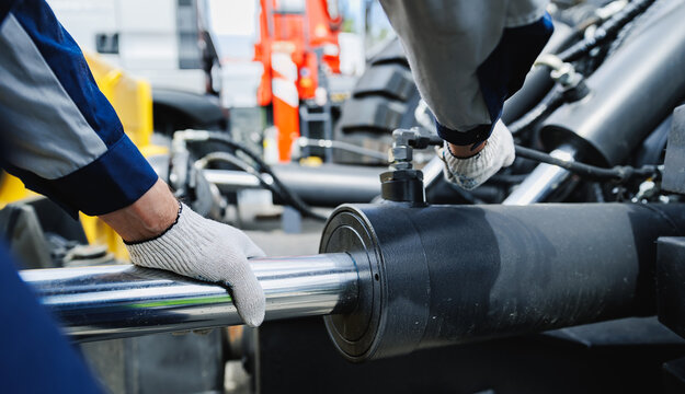 Worker mechanic check pipe system of hydraulic hose valves in industry machinery. Diagnostics and fix problem of truck