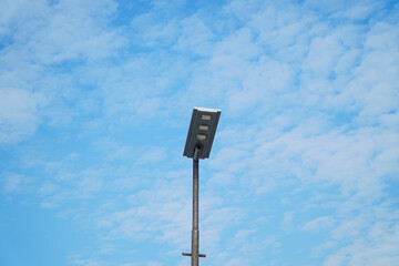 Modern street lighting pole isolated against a vibrant blue sky filled with fluffy clouds. The clean, minimalist design ensures versatility and seamless integration in various projects.