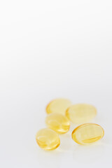Close-up of several fish oil Omega-3 gel capsules on light background. Yellow transparent capsules viewed from the front. Shallow depth of field, focused on the foreground. Copy space.