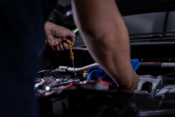 Young man inspecting the engine oil level of his car for regular maintenance and vehicle safety.