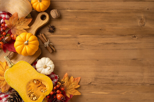 Top view of a Thanksgiving arrangement with pumpkins, autumn leaves, spices, and wooden background