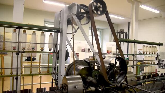 Vintage engine machinery with gears, belts, and wheels inside an old textile factory in Switzerland, showing industrial heritage and mechanical detail