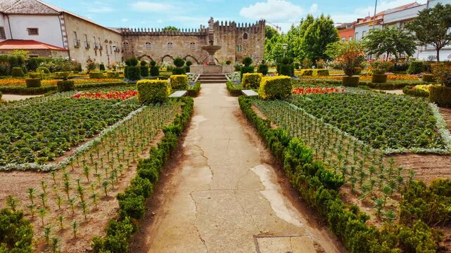 Santa Barbara Garden flourishes beside the crenellated battlements of Braga Castle with bright parterres framing Gothic arches in Braga, Portugal