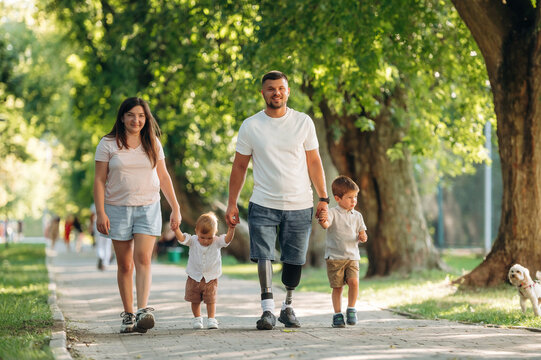 Smiling, enjoying the walk. Family of father that is amputee with prosthesis, mother and two kids