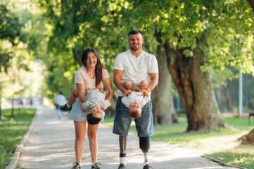 Front view, having a walk. Family of father that is amputee with prosthesis, mother and two kids