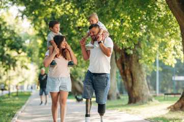 Obraz premium In the public park. Family of father that is amputee with prosthesis, mother and two kids
