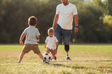 Dad on prosthesis is playing soccer with his two young sons