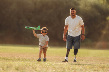 Obraz premium Active, running with toy plane. The amputee father is with his son on the field