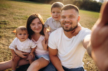 Fototapeta premium Selfie time, sitting. Mother, amputee father with prosthesis and kids are on the field