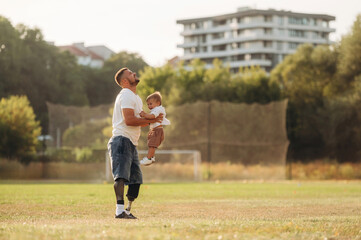 Feeling good, holding kid in hands. The amputee father is with his son on the field